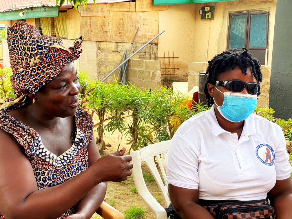 two women sitting next to each other. One person wears a medical mask