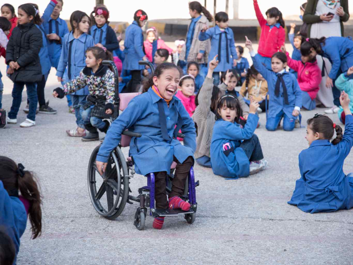 Ein Kind sitzt in einem Rollstuhl und lacht und spielt.
